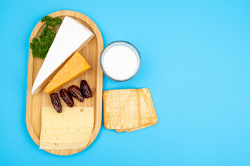 Blue background for holidays Shavuot, Pentecost. Milk, homemade cheese, bread and dates on a wooden tray.