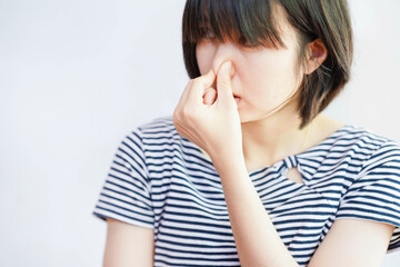 Woman showing dislike of bad smell by covering her nose.