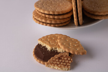 photo of a broken round cookie lying next to a plate of whole cookies