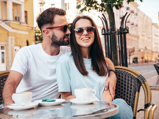 Smiling beautiful woman and her handsome boyfriend. Happy cheerful family. Couple drinking coffee in restaurant. They drinking tea at cafe in the street. Holding cup. Enjoying their date