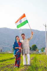 Indian farmer couple waving tricolor national flag at agriculture field.