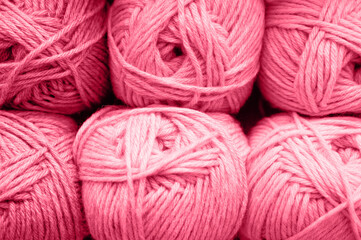 background of rows skeins of fluffy wool yarn for knitting soft red pink purple hue colors. toned in viva magenta, trend color of the year 2023