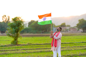 Indian farmer holding indian flag at agriculture field.