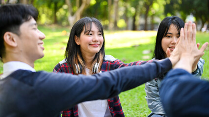 Cheerful Asian friends putting hands together as a teamwork. celebrating, cheering up