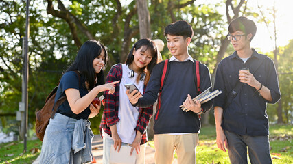 Group of happy Asian college students enjoy talking and walking in the campus's park together.