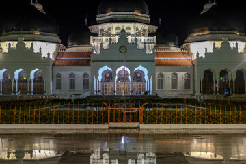Fototapeta premium The night atmosphere at the Baiturrahman Grand Mosque. Reflection of the Baiturrahman Grand Mosque building at night. Banda Aceh.
