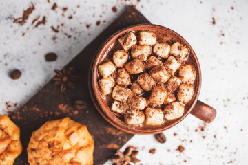 Hot chocolate drink with marshmallows in a cup and sweet bakery eclair dessert sprinkled with cocoa powder, top view