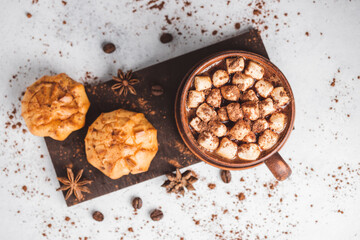 Hot chocolate drink with marshmallows in a cup and sweet bakery eclair dessert sprinkled with cocoa powder, top view