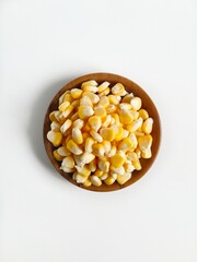 Shelled sweet corn in a wooden plate and white background. Photo from top view