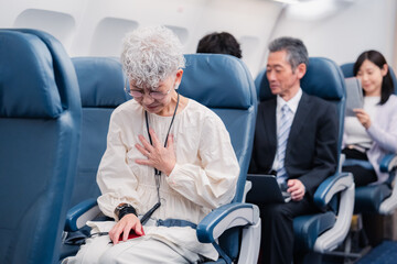 飛行機の機内で体調不良に苦しむ高齢の女性