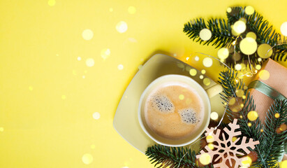 Fototapeta na wymiar cozy new year layout with a cup of coffee and new year decorations and christmas lights on a yellow background with bokeh. copy space.