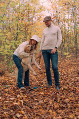 young happy cheerful couple playing with their labrador retriever dog outdoors in autumn forest. Family with a pet having fun