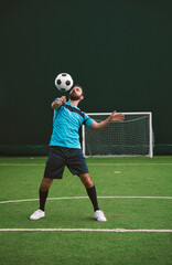 Cinematic image of a soccer freestyle player making tricks with the ball on a artificial grass court indoor. Concept about sport and people lifestyle	
