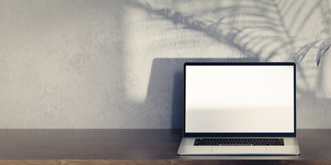 Laptop mockup on wooden table, grey plaster wall and palm tree shadow. Laptop with blank screen mockup. Front view laptop on work table, grey background. copy space