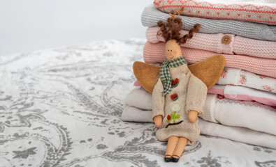 a stack of baby things in pink and gray colors and an angel toy on a gray and white background....