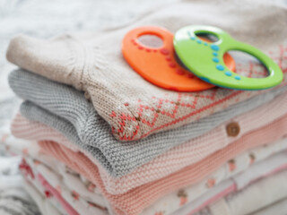 Knitted baby clothes from natural materials close-up, soft focus and children's toys. Knitting, needlework, handwork, hobby.