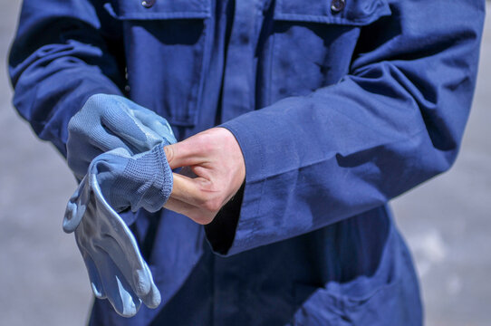 Workman In Blue Overalls While Wearing Protective Gloves - Close Up
