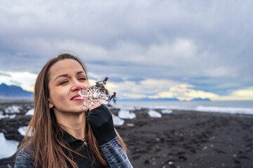 young girl woman licks ice at Jökulsárlón glacier at the beach