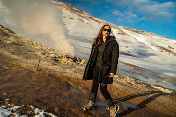 young woman smiling and watching in camera at hverir geothermal fumarole