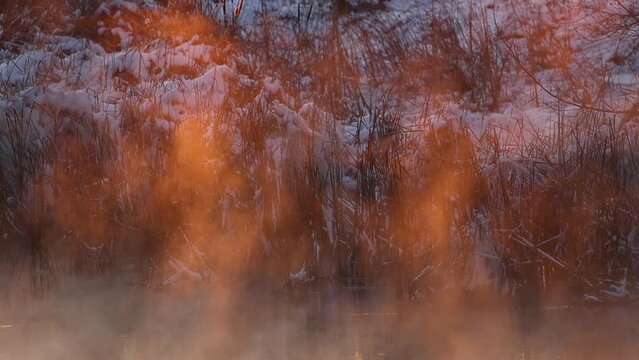 steam in sunset colors over a winter river