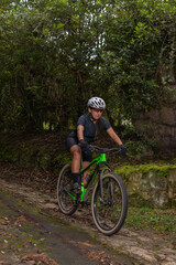 Sporty woman, wearing goggles and helmet, riding her bike while descending a mountain on a rustic path