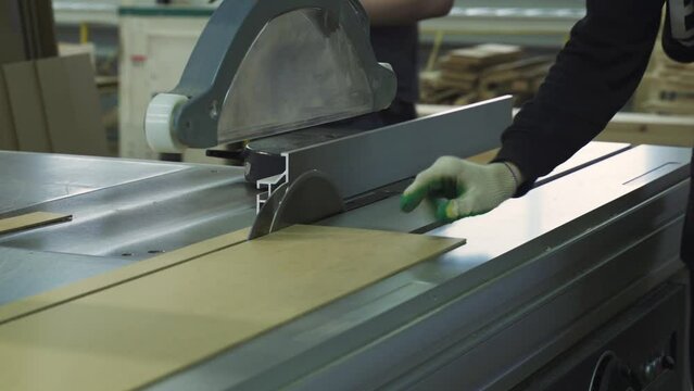 A circular saw cuts through a hardboard wood panel. Woodworking. Furniture manufacturing.