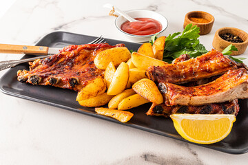 Delicious pork ribs and grilled potato slices served on a ceramic rectangular dish with parsley. the concept of serving the food. menu.