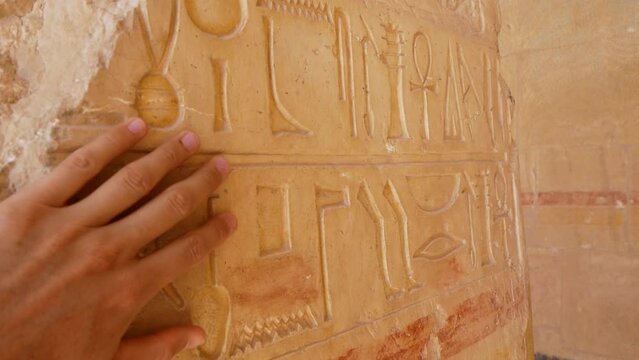 Hand Touching Carved Ancient Hieroglyphs On Stone Column Of Egyptian Temple