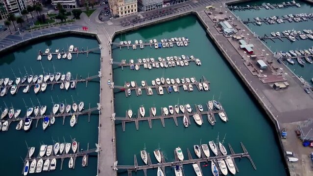 spectacular and unique aerial perspective overhead drone shot where we see a marina with its white boats on the blue water of the elegant place