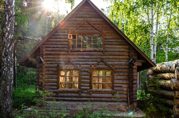 An old village house made of logs in the forest in the early morning.
