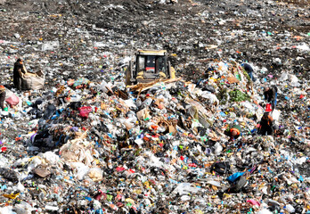 Solid waste disposal and landfill gas collection. Landfill with solid household waste. Dozer on Garbage dump with waste plastic and polyethylene. Homeless people looking for food in a landfill