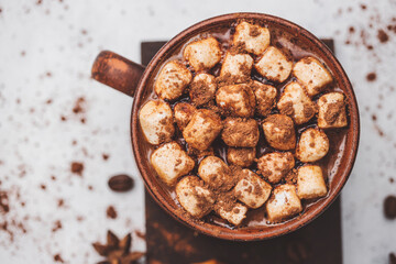 Hot chocolate drink with marshmallows in a cup and sweet bakery eclair dessert sprinkled with cocoa powder, top view