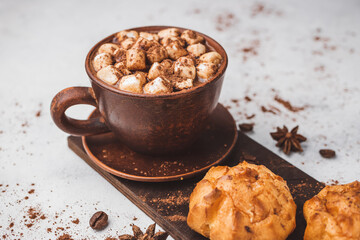 Hot chocolate drink with marshmallows in a cup and sweet bakery eclair dessert sprinkled with cocoa...