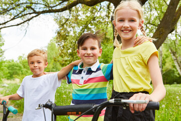 Multiracial friends standing with bicycles in garden
