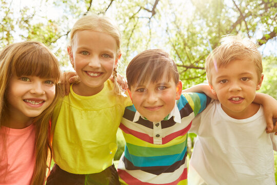 Kids with arms around standing in summer at garden