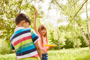 Smiling girl making soap bubble by male friend