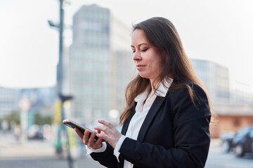 Smart businesswoman using smartphone in the city