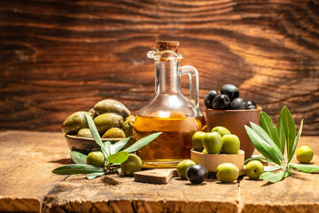 Olive oil in bottles with black and green olives and leaves. extra virgin olive oil jars on a wooden background. place for text