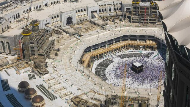 Time lapse of Muslim pilgrims circling around the holy Kaaba at noon and praying inside al Masjid al Haram in Mecca, Saudi Arabia.  Tilt down motion timelapse. Prores UHD