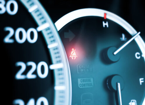 Fasten seatbelt warning light on car dashboard with a seat belt illuminated icon on background