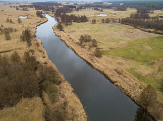 Fototapeta na wymiar Ein Fluss fließt durch eine Graslandschaft mit einzelnen Bäumen in Großpolen (Luftbild/Drohnenfoto)
