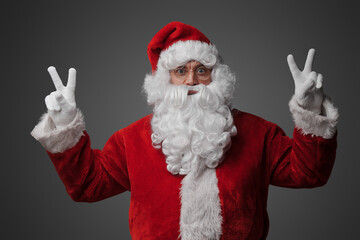 Fototapeta na wymiar Portrait of isolated on grey santa claus with glasses dressed in red suit and hat.
