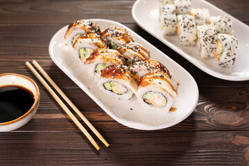 Sushi set with eel and sesame on white plate on wooden background with copy space. Japanese food. teriyaki sauce on sushi