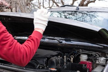 a man opens the hood of a car for repairs. Car repair and maintenance