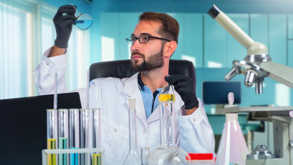 Doctor laboratory. Man physician synthesizes new medicine. Guy in white coat sits at table with flasks. Microscope and laptop near doctor. Man pharmacologist holds glass flasks. Doctor pharmacologist