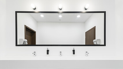 Nowoczesna toaleta z dużym oświetlonym lustrem. Szeroka umywalka z kranami na kilka osób. Jasna i przestronna łazienka.