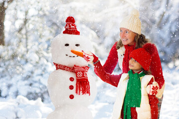 Child building snowman. Kids build snow man.