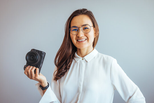Beautiful girl photographer is taking pictures with dslr camera. Artistic young photographer smiling in her office. Happy young woman holding a dslr camera in her hands. 