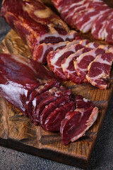 smoked pieces of meat on a wooden board with several cut pieces