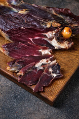 Cutting smoked lamb leg on a wooden board